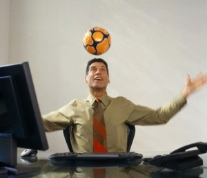 Businessman Heading Soccer Ball at Desk
